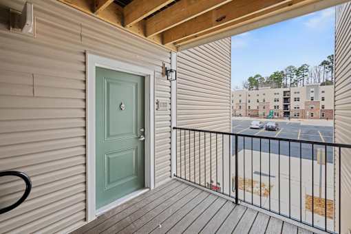 A balcony with a green door and a black railing.