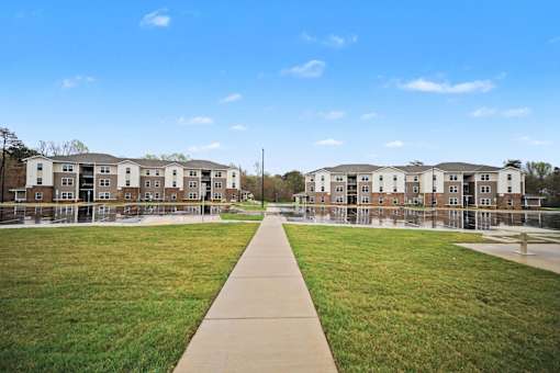 A long concrete walkway leads to apartment buildings.
