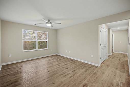 A room with a ceiling fan and a window with a picture hanging on the wall.