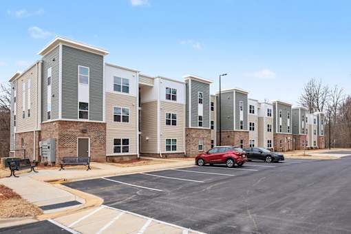 A parking lot in front of a building with cars parked.