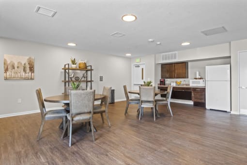 a dining area with a table and chairs and a kitchen in the background