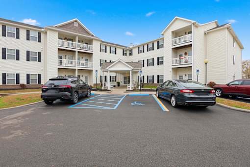 A black SUV is parked in a parking lot in front of a white apartment building.