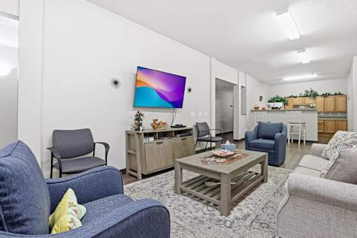 A living room with a blue couch and a flat screen TV mounted on the wall.