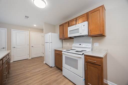 A kitchen with a white stove and a white microwave above it.