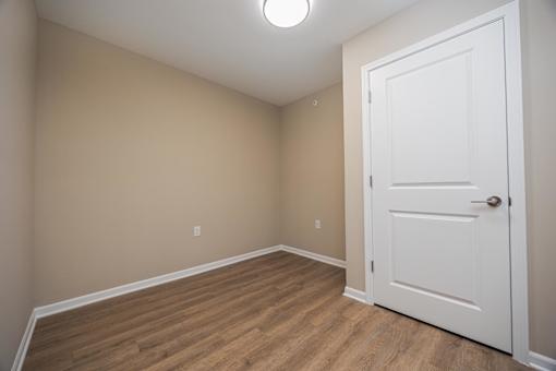 A room with a white door and wooden floor.