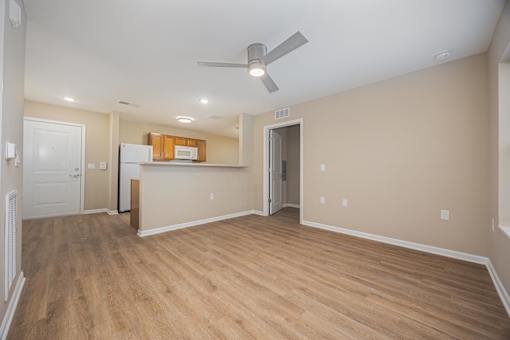A room with a ceiling fan and wooden flooring.