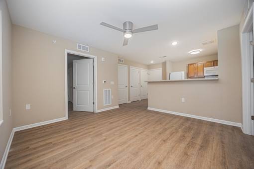 A room with a ceiling fan and wooden flooring.