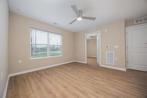 A room with a ceiling fan and wooden flooring.
