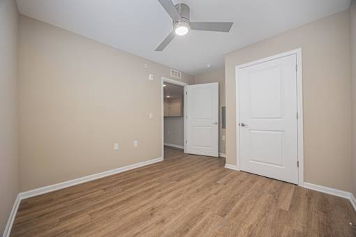 A room with a ceiling fan and wooden flooring.