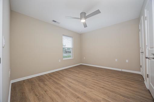 A room with a ceiling fan and wooden flooring.