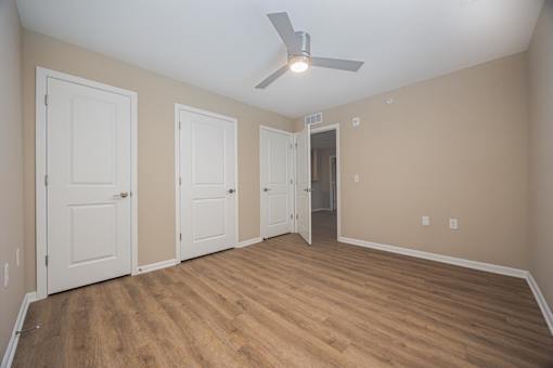 A room with a ceiling fan and wooden flooring.