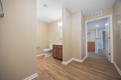 A bathroom with a toilet, sink, and wooden floors.