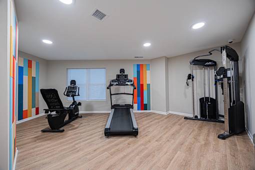 A gym with a treadmill, elliptical trainer, and a stationary bike.