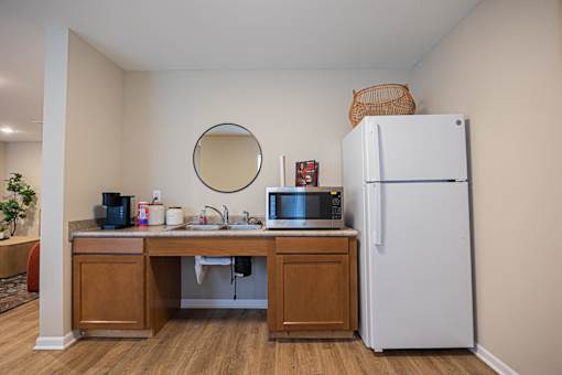 A kitchen with a white refrigerator and a round mirror on the wall.