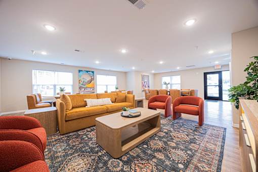 A living room with a yellow couch and red chairs.