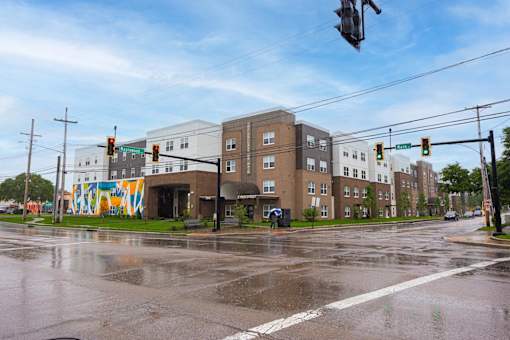 A wet street with a traffic light and a building with a mural on the side.