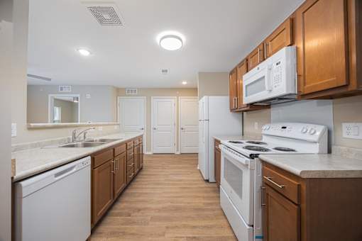 A kitchen with white appliances and wooden cabinets.