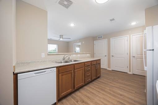 A kitchen with a white dishwasher and wooden cabinets.