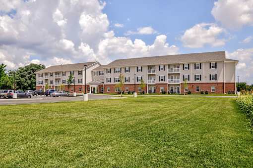 A large apartment complex with a grassy field in front.