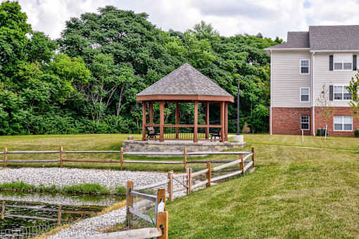 A gazebo is situated in a grassy area in front of a house.