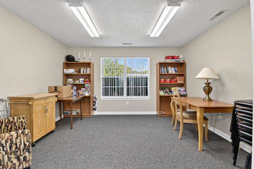 A room with a desk, chairs, and bookshelves.