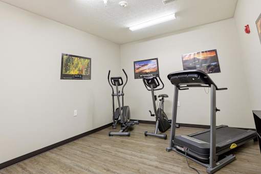 A room with a treadmill, elliptical trainer and a stationary bike.