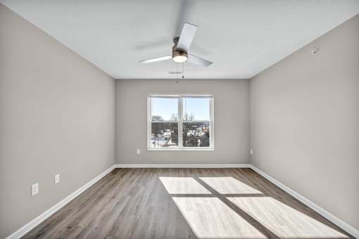 A room with a ceiling fan and a window with a view of a snowy landscape.