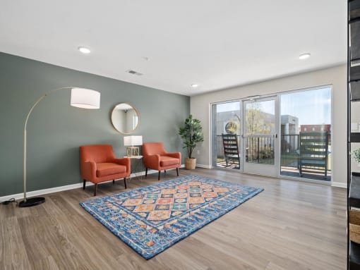 a living room with two orange chairs and a rug   and a sliding glass