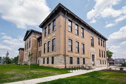 A large, two-story building with a flat roof and a mix of stone and brick exterior.