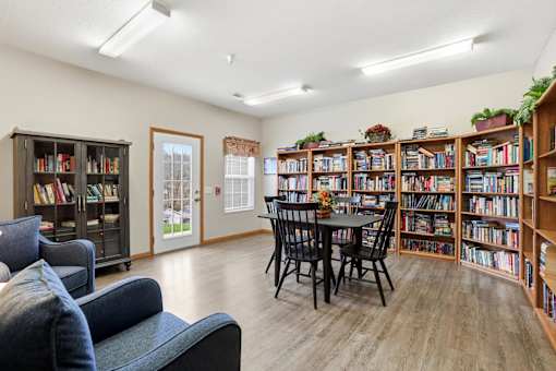 A room with a black table surrounded by black chairs and a bookshelf filled with books.