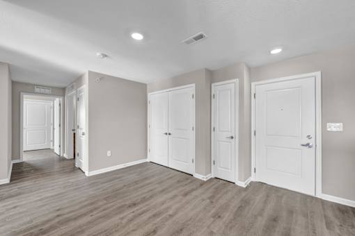 A room with white doors and a light brown floor.