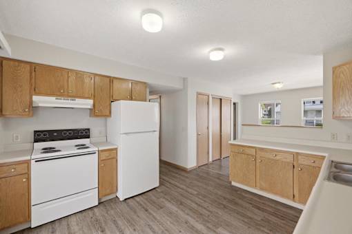 A kitchen with white appliances and wooden cabinets.