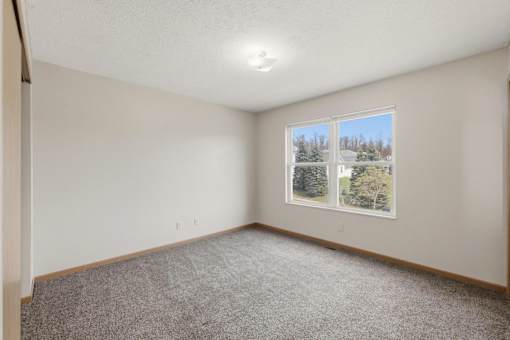 A room with a window showing a view of trees and a house.