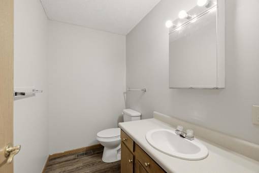 A bathroom with a toilet, sink, and mirror.