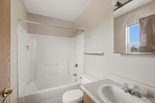 A white bathroom with a toilet, sink, and bathtub.