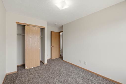 A room with a carpeted floor and two open closet doors.