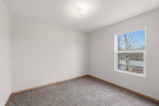 Empty room with a window showing a tree and a building outside.