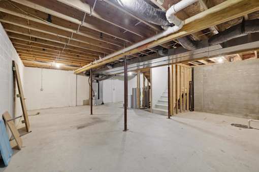 A room under construction with exposed pipes and wooden beams.