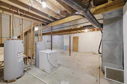 A room under construction with a furnace and air conditioner.