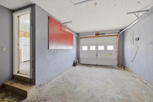 A room with a garage door and a window with blinds.