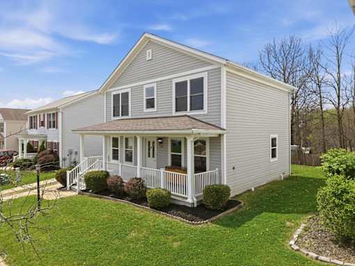 A house with a grey siding and a white porch.