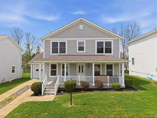A house with a grey roof and white walls with a porch.