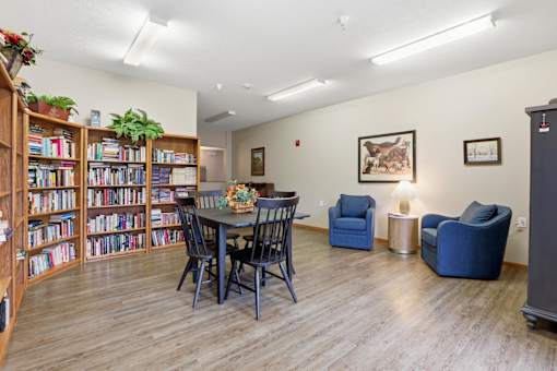 A room with a table, chairs, and a bookshelf.
