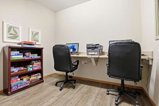 A room with two chairs, a desk, and a bookshelf filled with books.