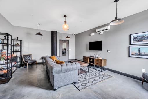 a living room with a gray couch and a tv on the wall