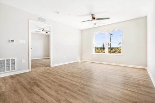 an empty living room with a ceiling fan and a window