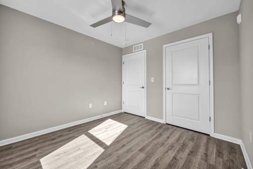 A room with a ceiling fan and two doors.
