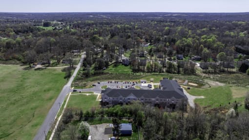 an aerial view of a house and a mansion with a green field and trees
