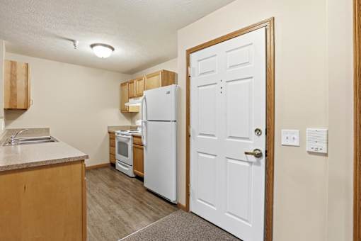 A kitchen with a white refrigerator and wooden cabinets.