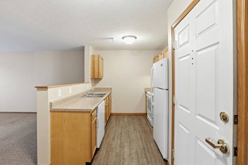 A kitchen with white appliances and wooden cabinets.